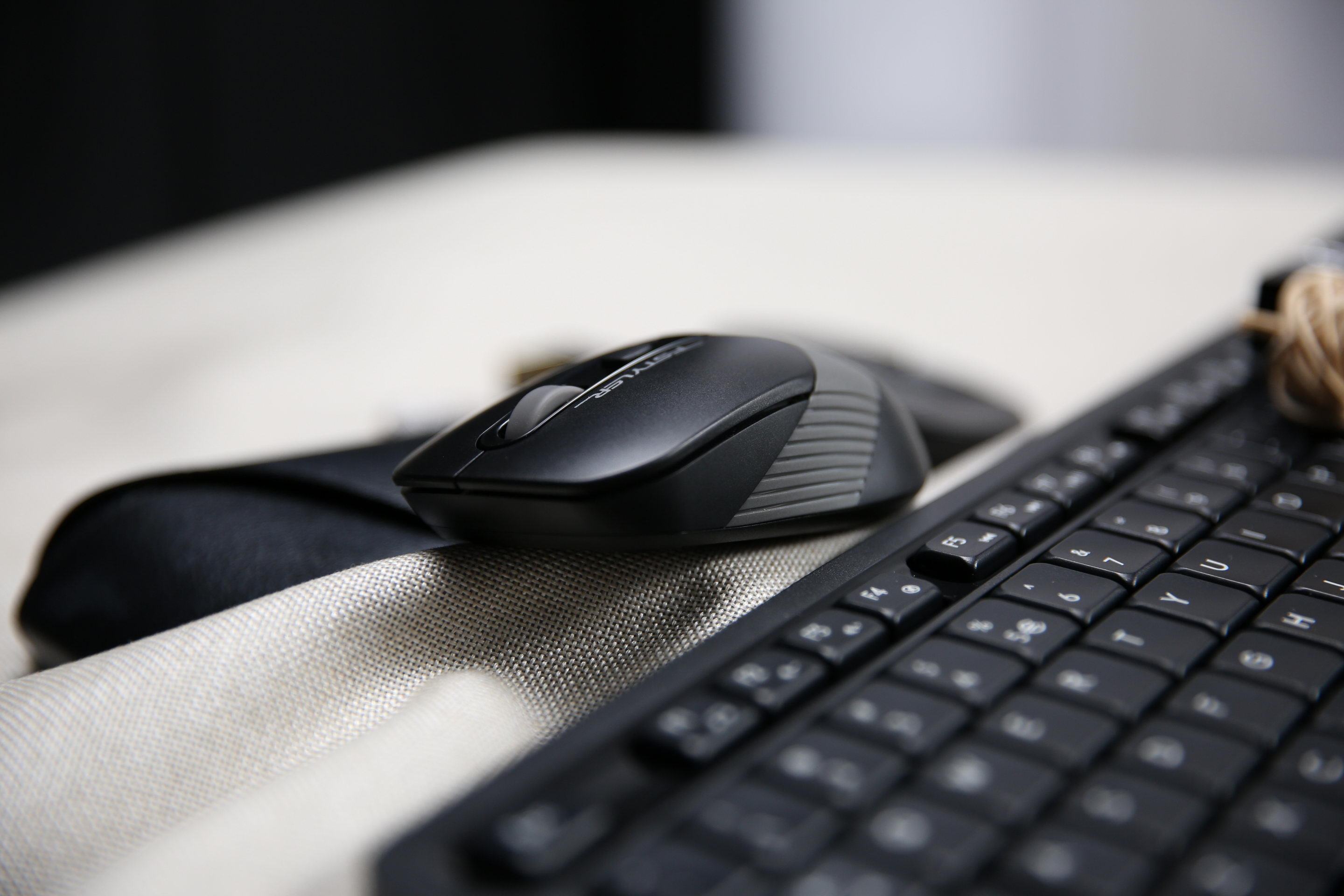 FG10S grey mouse beside a keyboard, showing the textured side grip