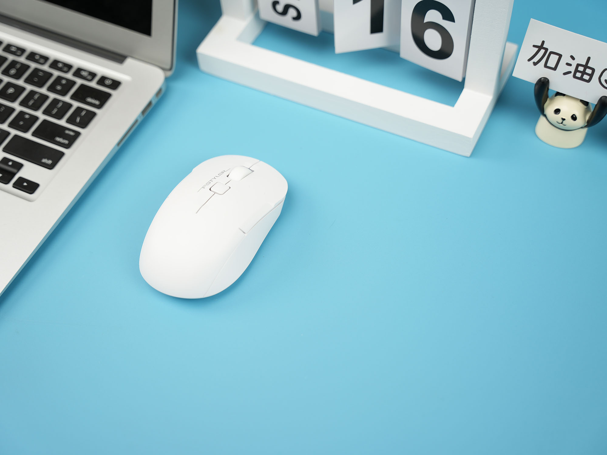 FG16CS Air2 white mouse on a blue desk beside a laptop